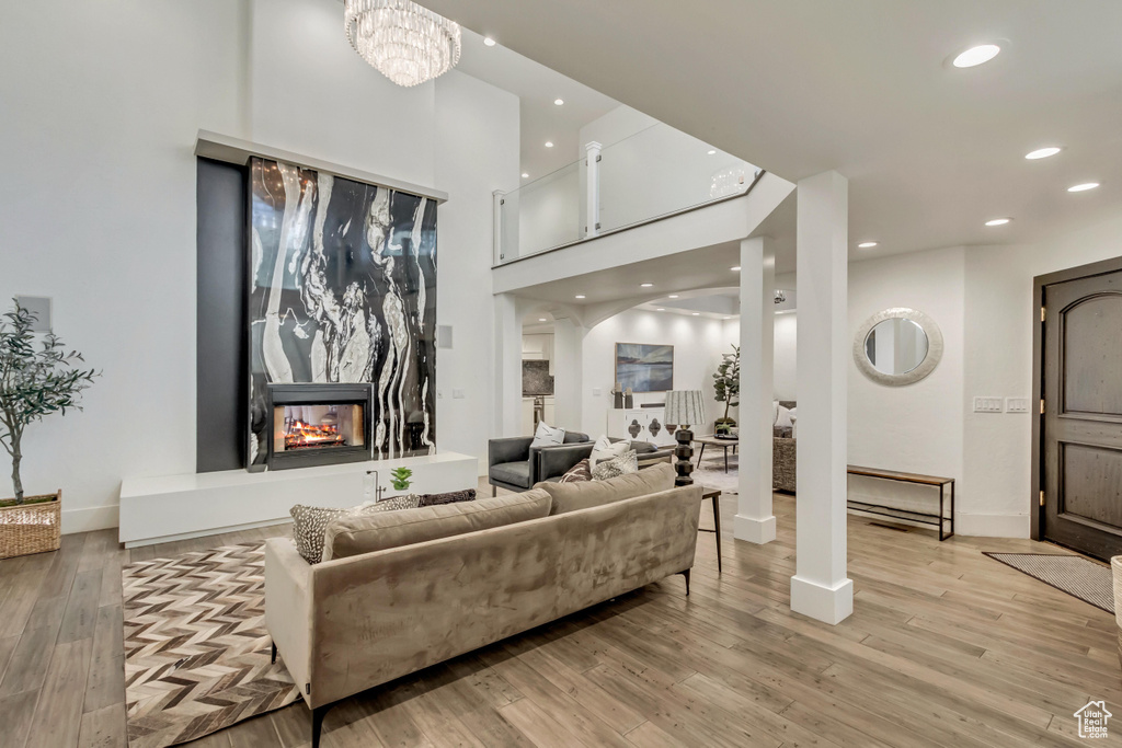 Living area with arched walkways, a multi sided fireplace, recessed lighting, and light wood-style floors