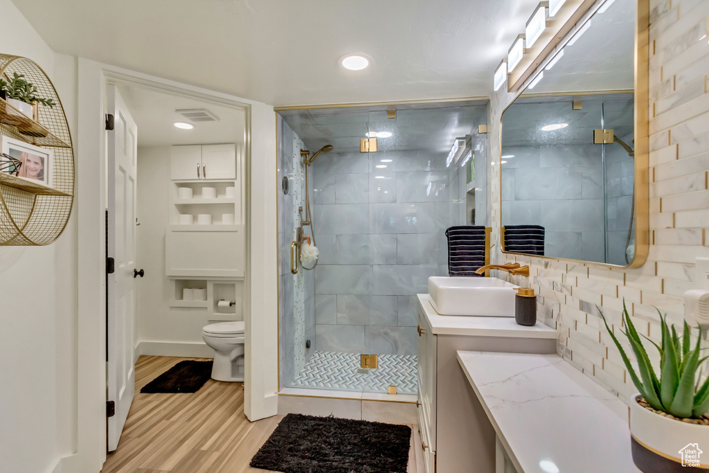 Bathroom featuring a stall shower, toilet, vanity, wood finished floors, and visible vents