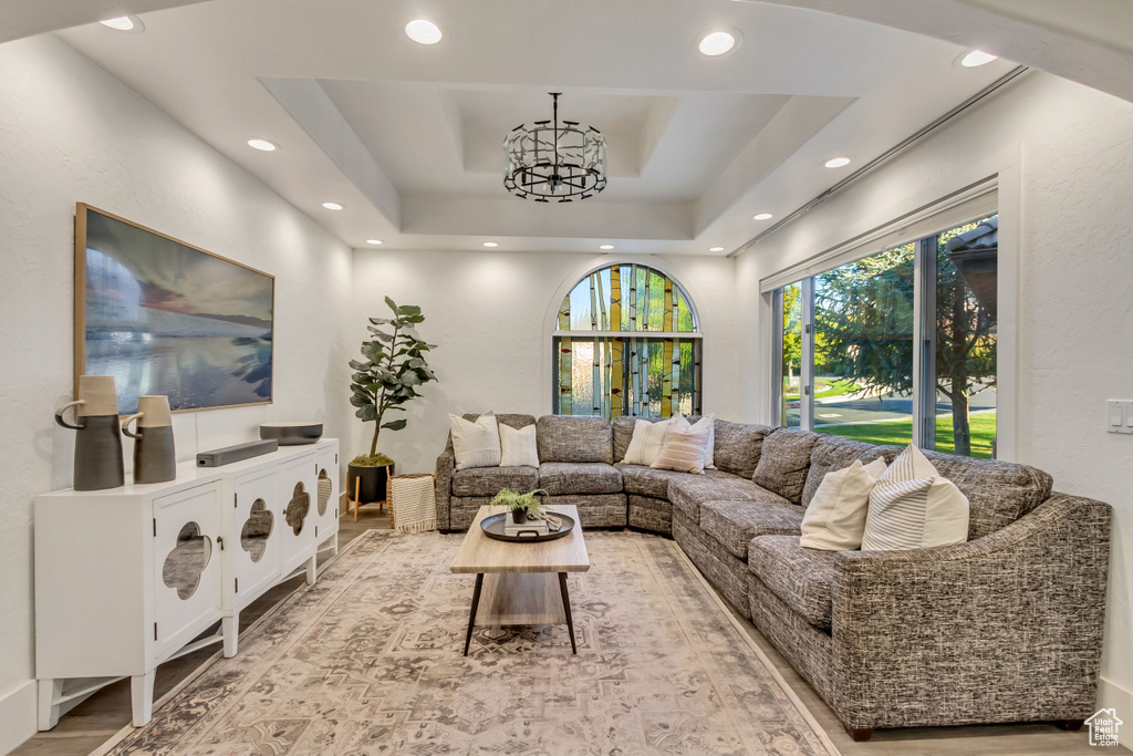 Living area with a tray ceiling, recessed lighting, and a chandelier