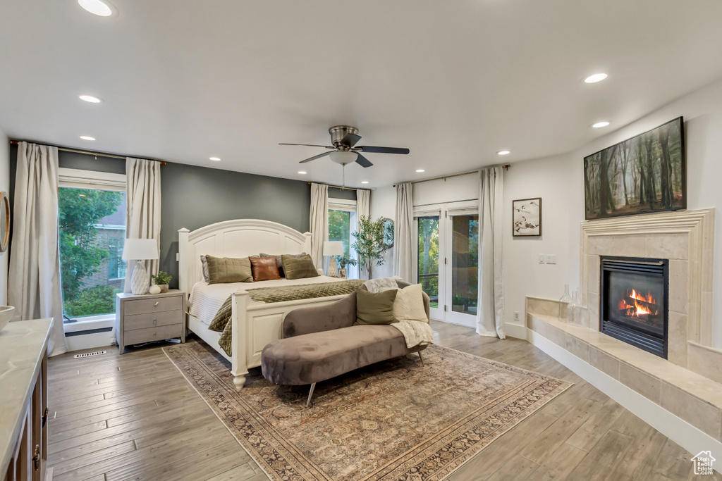 Bedroom featuring recessed lighting, baseboards, access to exterior, light wood-style flooring, and a tile fireplace