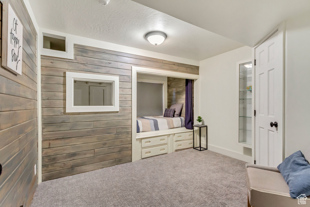 Interior space featuring wooden walls, carpet floors, and a textured ceiling