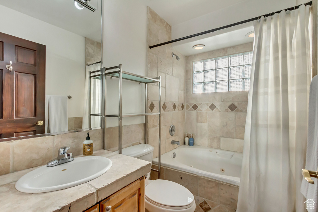 Bathroom featuring tile walls, toilet, vanity, tasteful backsplash, and tiled shower / bath