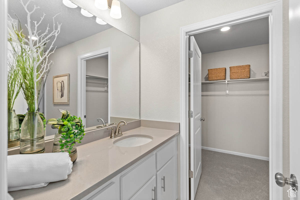 Bathroom with vanity, a walk in closet, and baseboards