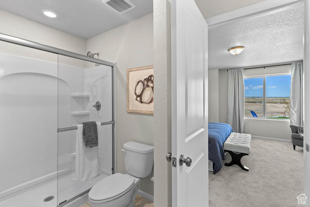 Full bathroom with toilet, a stall shower, baseboards, and visible vents