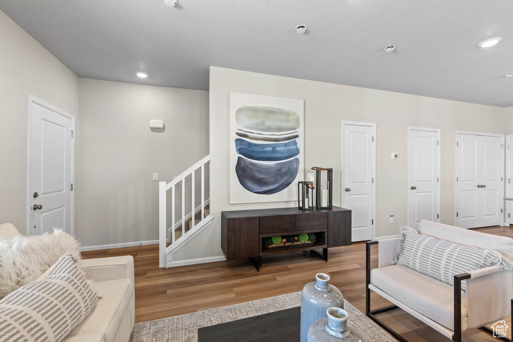 Living area with recessed lighting, baseboards, stairway, and wood finished floors