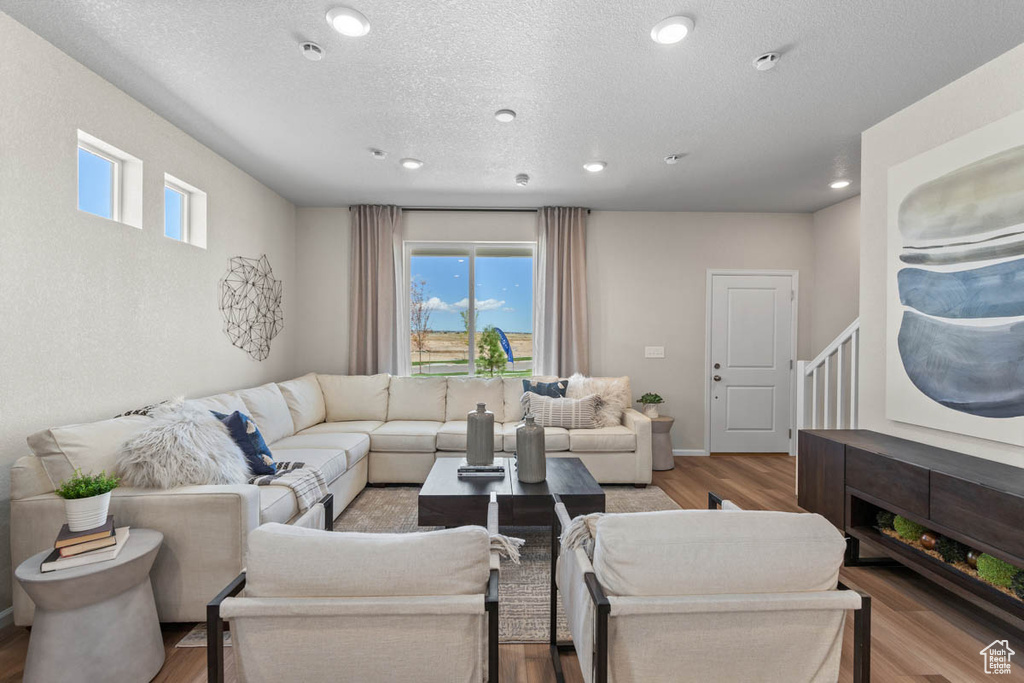 Living area featuring recessed lighting, a textured ceiling, baseboards, and wood finished floors