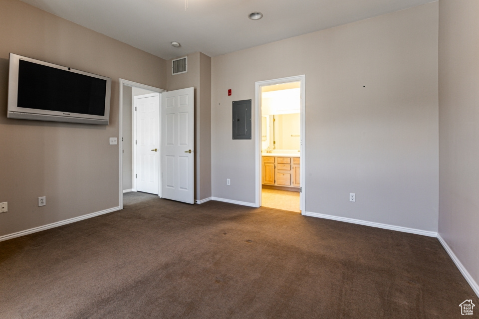 Unfurnished bedroom with dark carpet, baseboards, visible vents, and electric panel