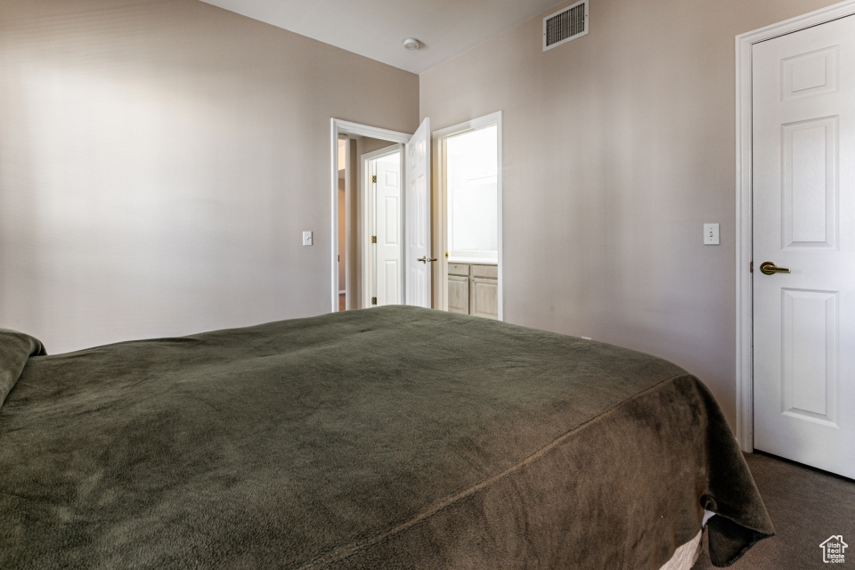 Bedroom with visible vents and dark carpet