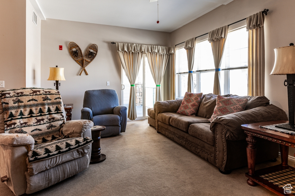 Carpeted living area featuring a ceiling fan and visible vents