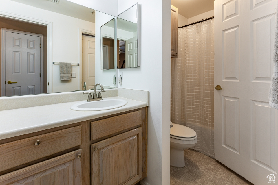 Bathroom with curtained shower, toilet, and vanity