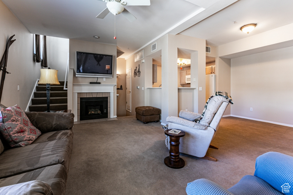 Living room featuring baseboards, carpet floors, visible vents, a ceiling fan, and a tile fireplace