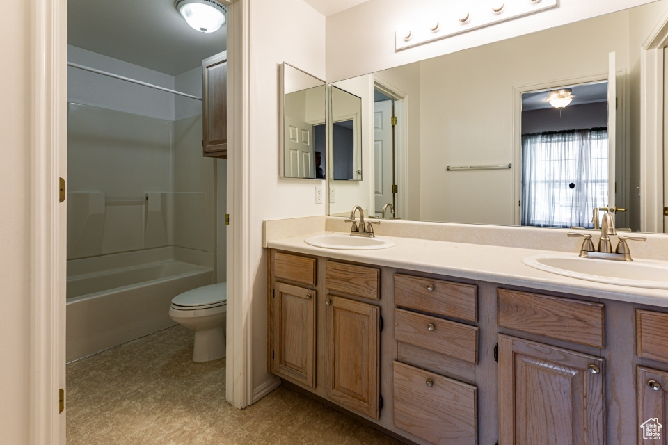 Full bathroom featuring double vanity, a sink, toilet, and shower / washtub combination