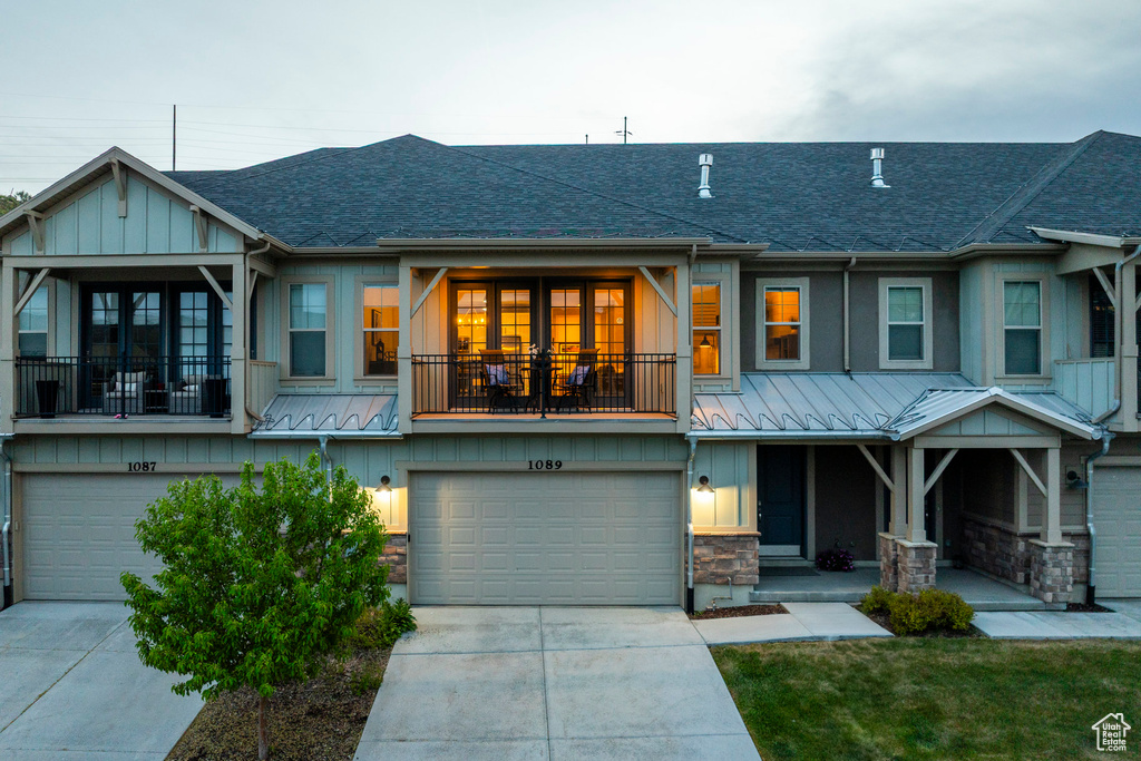 Multi unit property with roof with shingles, a garage, and board and batten siding