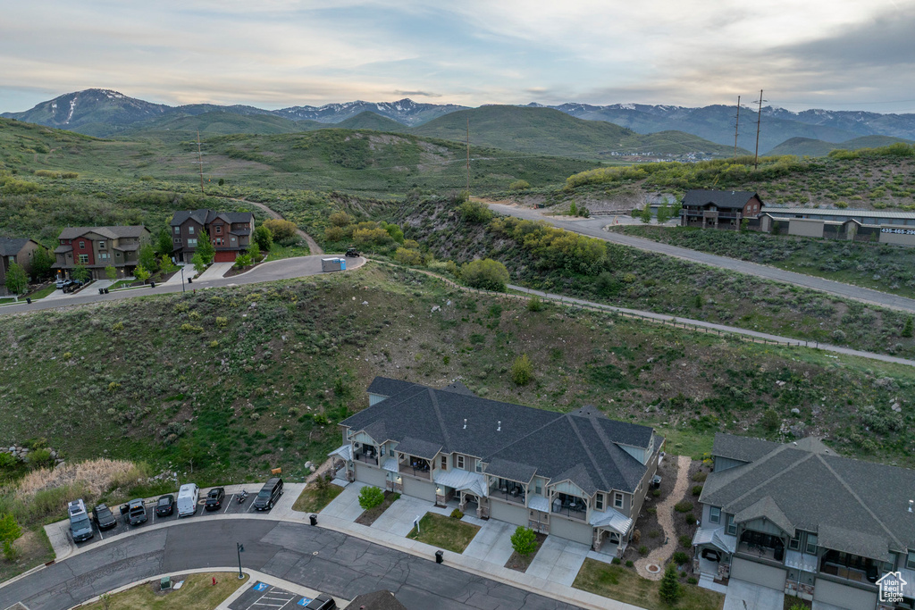 Aerial view of property and surrounding area featuring a mountainous background and nearby suburban area