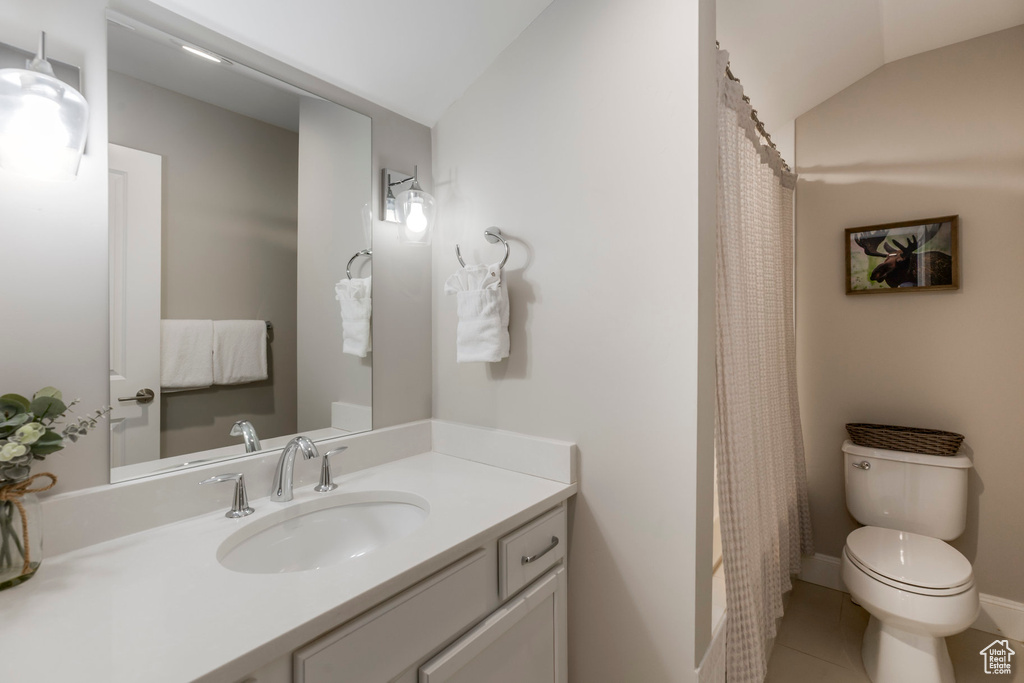 Full bathroom featuring lofted ceiling, vanity, toilet, and tile patterned flooring