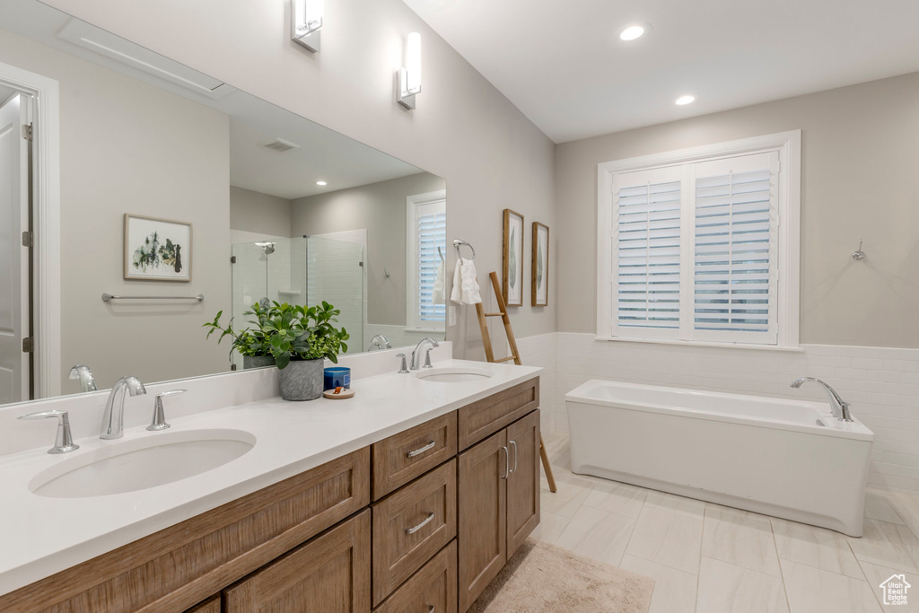 Bathroom featuring a shower stall, a bathtub, double vanity, and recessed lighting
