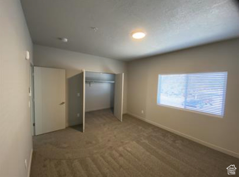 Unfurnished bedroom with a closet, carpet flooring, and baseboards