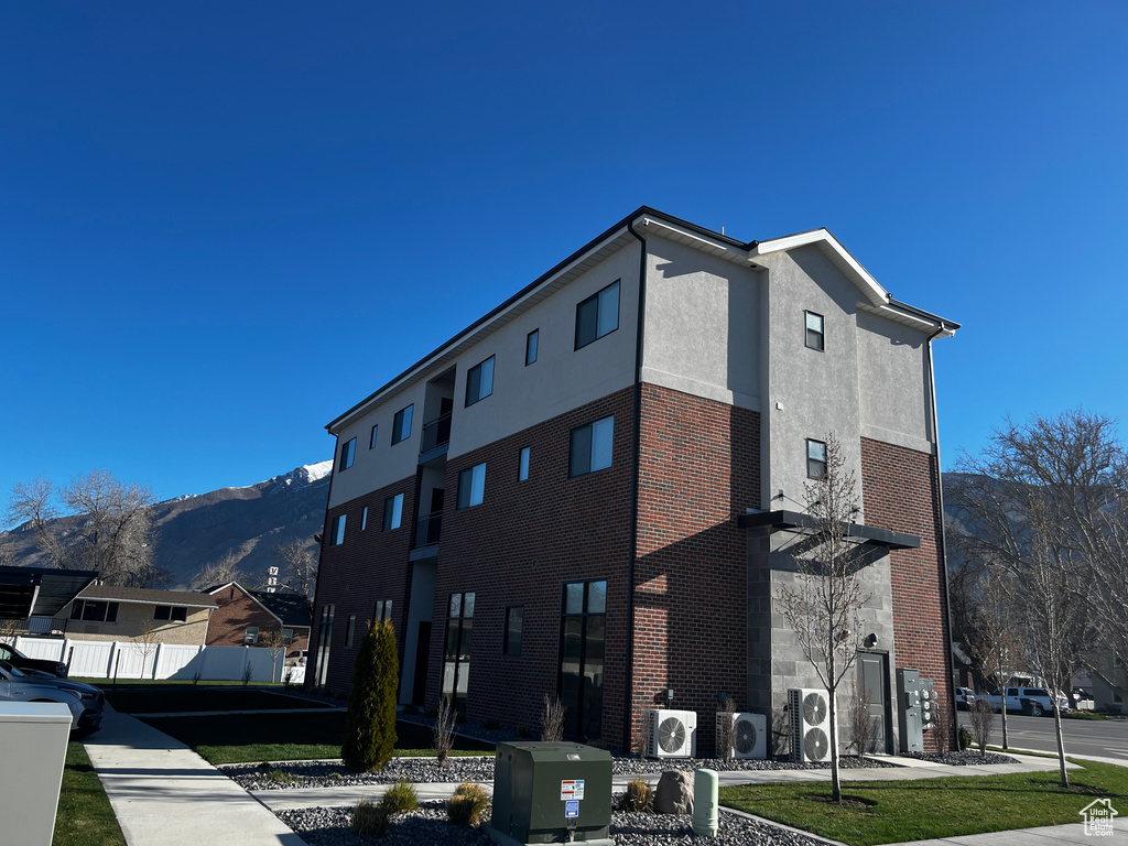View of building exterior featuring ac unit, a mountain view, and fence