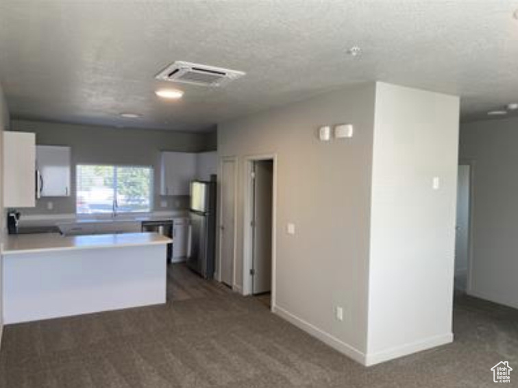 Kitchen featuring carpet flooring, visible vents, a peninsula, and freestanding refrigerator