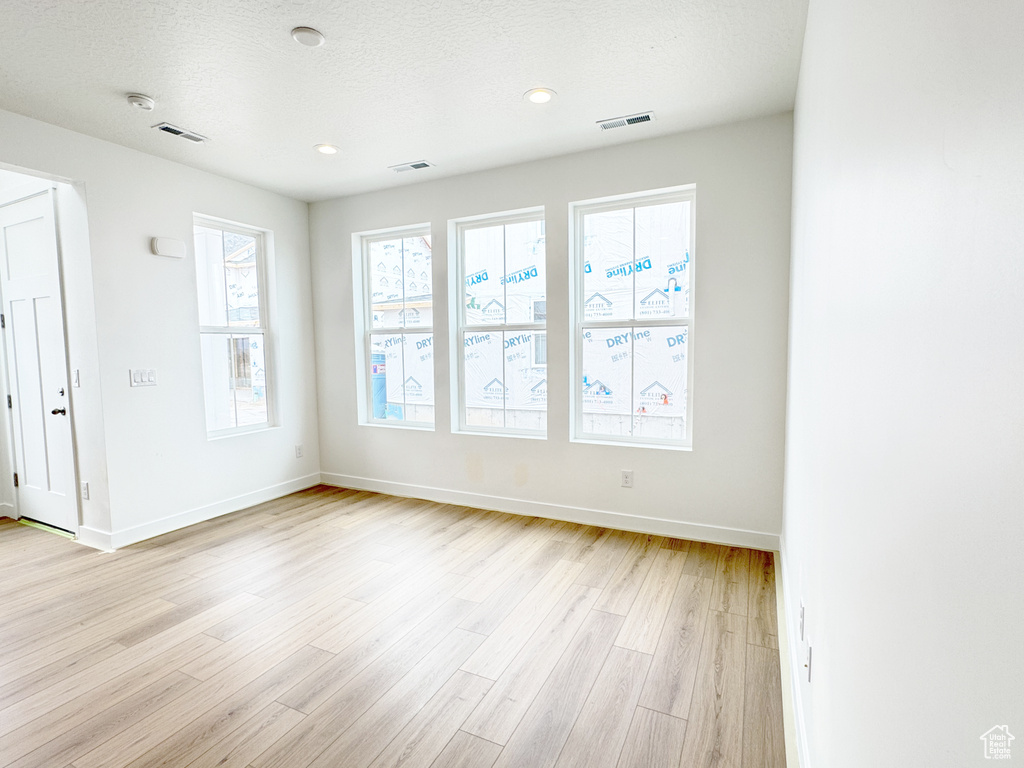 Spare room with light wood-type flooring, baseboards, and visible vents