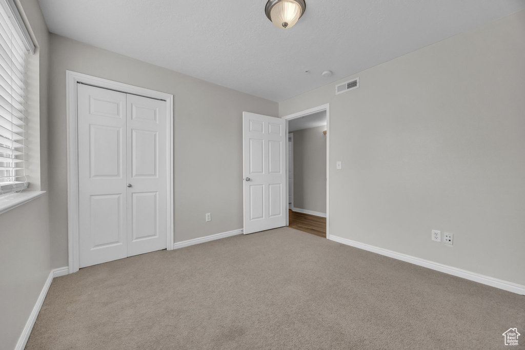 Unfurnished bedroom featuring a closet, carpet floors, visible vents, and baseboards