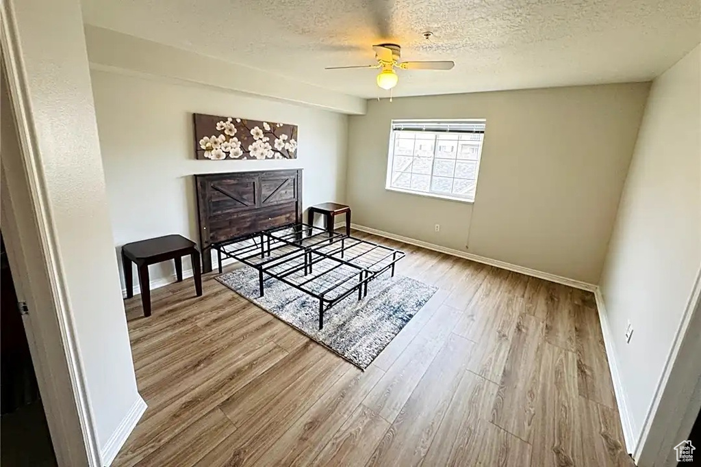 Bedroom featuring baseboards, a ceiling fan, wood finished floors, and a textured ceiling