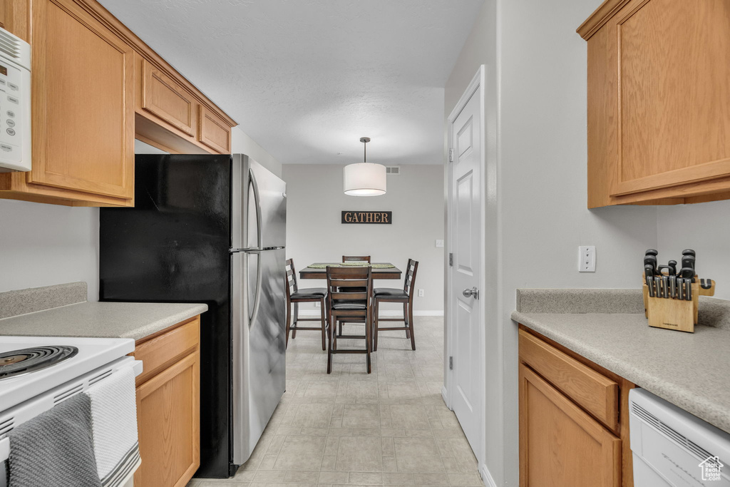 Kitchen featuring pendant lighting, light countertops, and white appliances
