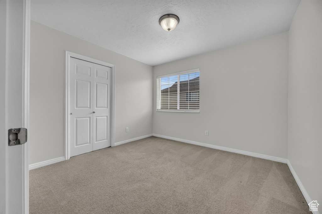 Carpeted spare room featuring baseboards and a textured ceiling