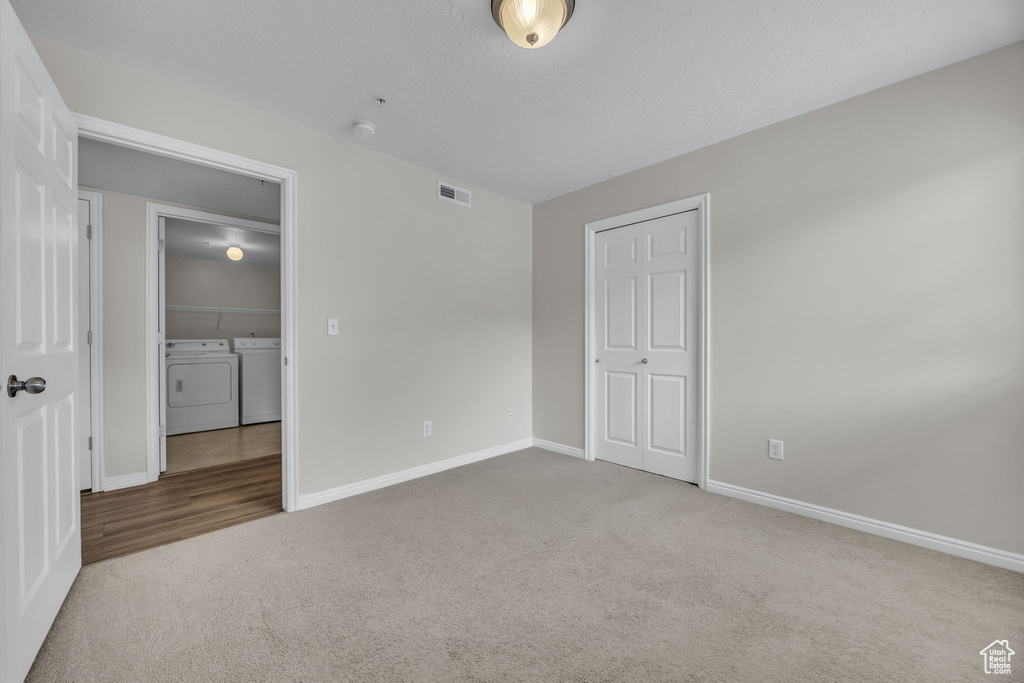 Unfurnished bedroom with carpet, baseboards, separate washer and dryer, and visible vents