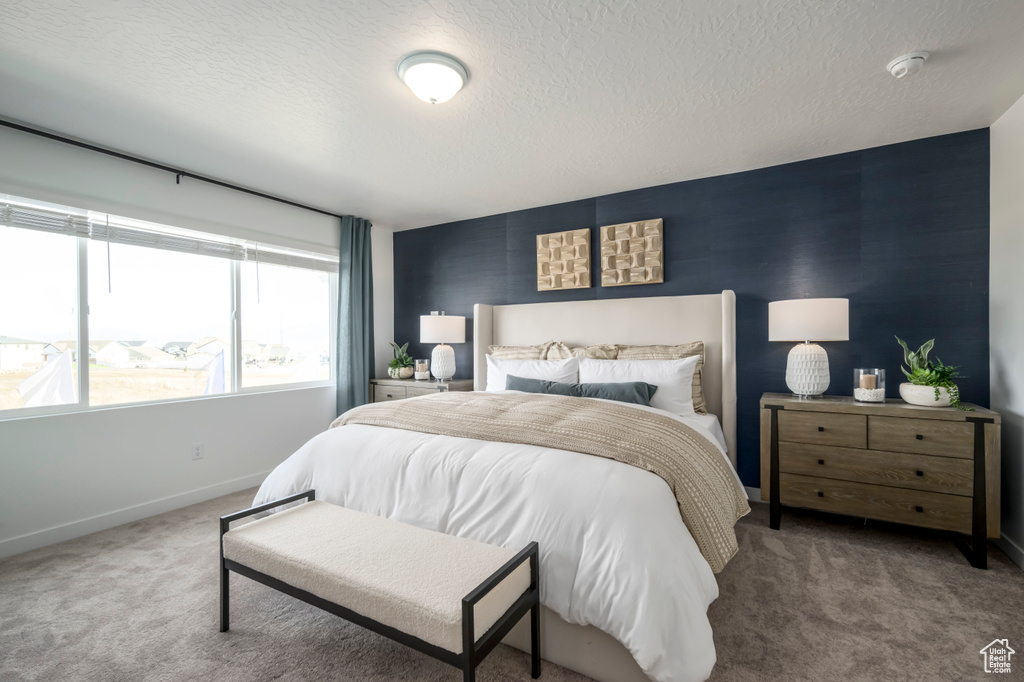 Carpeted bedroom featuring baseboards and a textured ceiling