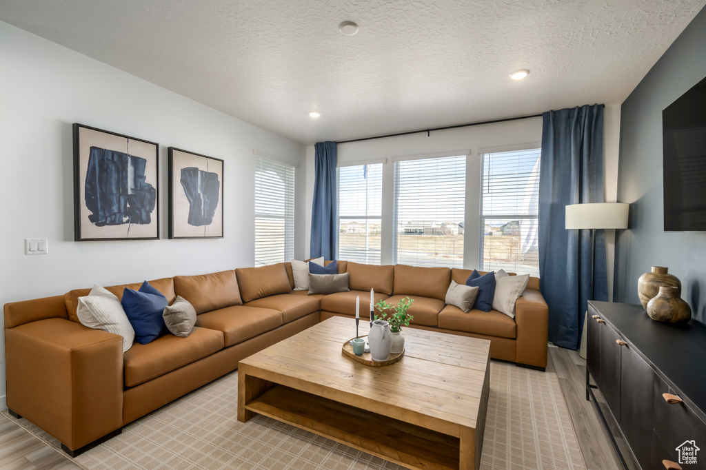 Living room featuring a textured ceiling, recessed lighting, and light wood finished floors
