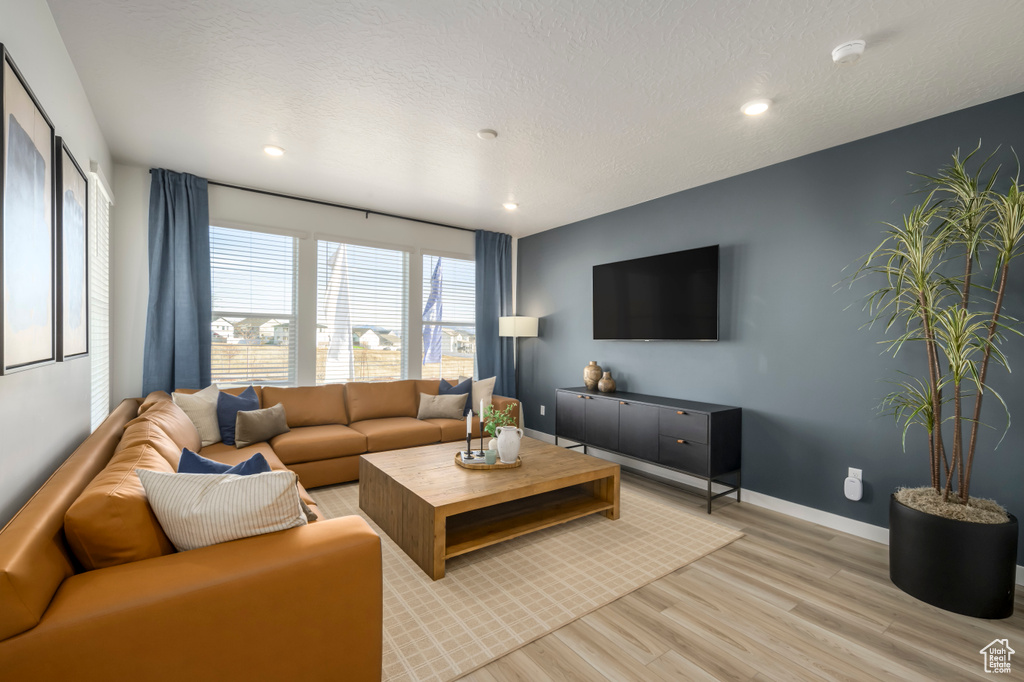 Living area with baseboards, a textured ceiling, recessed lighting, and light wood-style floors