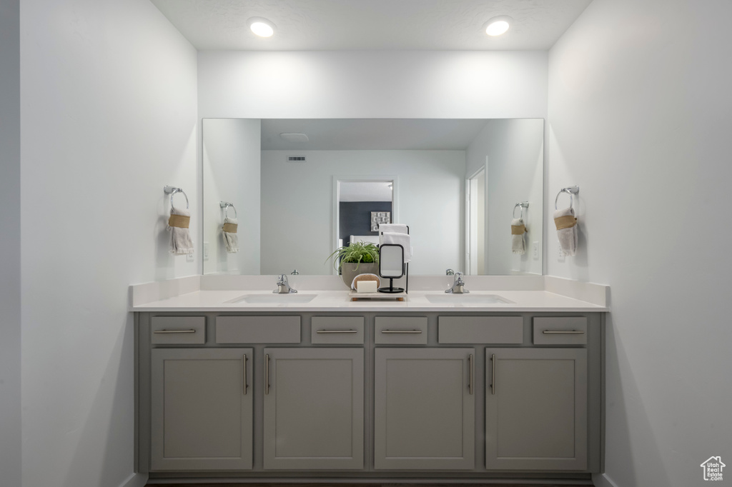 Full bath with double vanity, visible vents, baseboards, and a sink