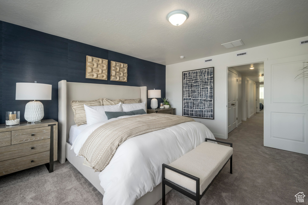 Bedroom with visible vents, carpet, and a textured ceiling