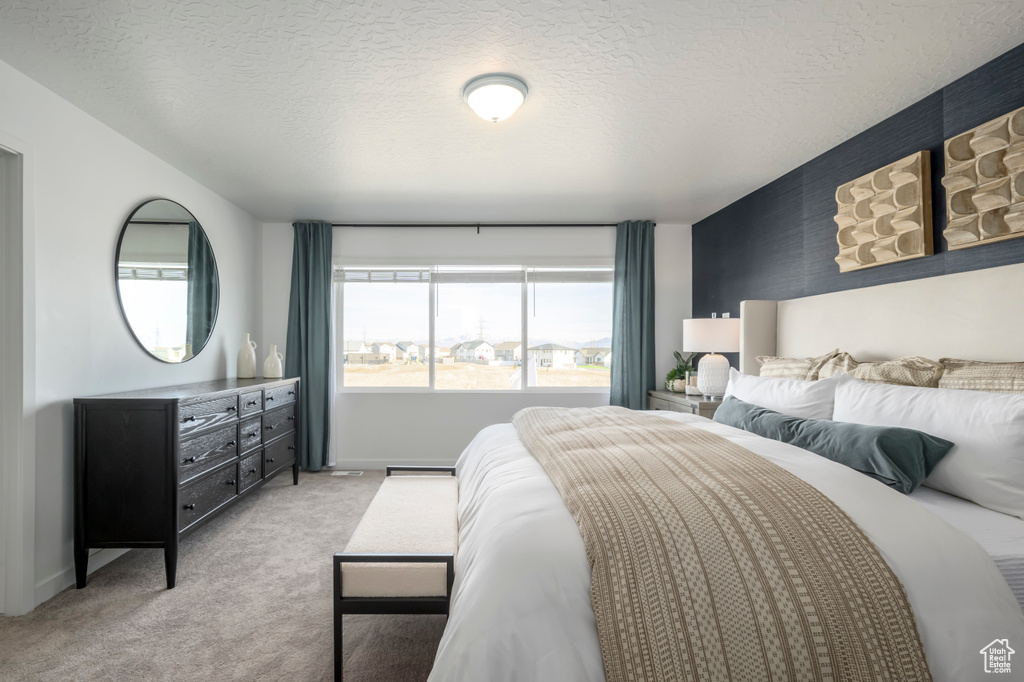 Bedroom featuring baseboards, a textured ceiling, and light carpet