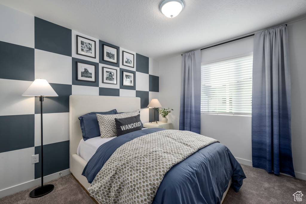 Carpeted bedroom featuring baseboards and a textured ceiling