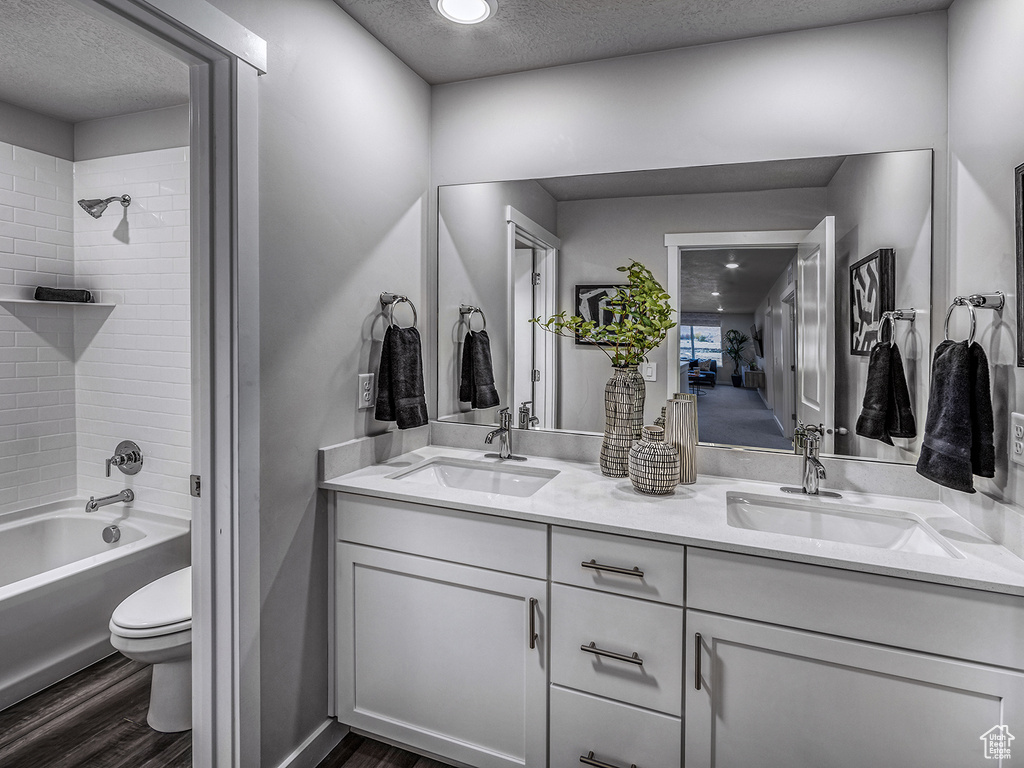 Full bath with a textured ceiling, wood finished floors, and a sink