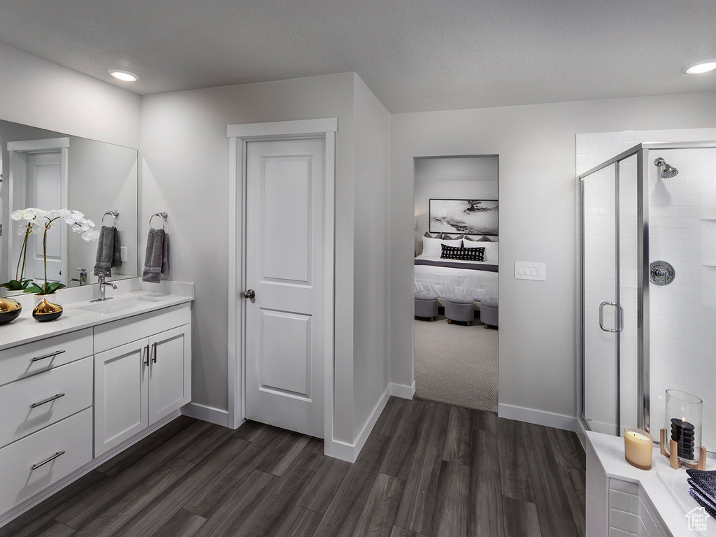 Ensuite bathroom featuring vanity, wood finished floors, baseboards, a shower stall, and ensuite bathroom
