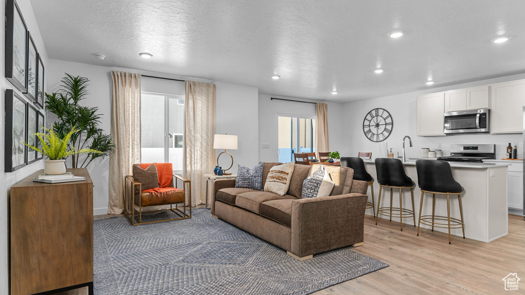 Living area with recessed lighting, a textured ceiling, and light wood-type flooring
