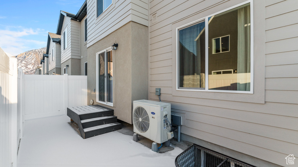 View of patio with ac unit, fence, and a mountain view