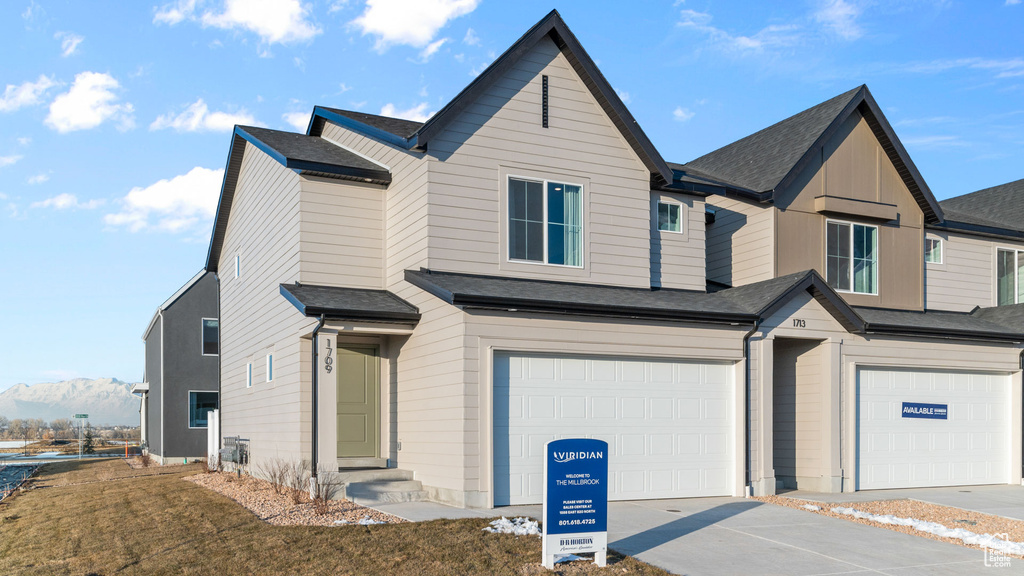 View of front of house featuring driveway, an attached garage, and roof with shingles