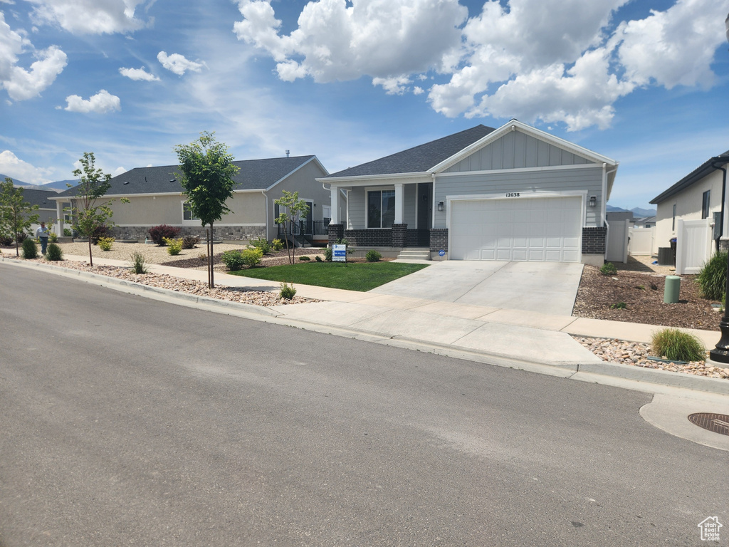 View of front facade with an attached garage, board and batten siding, concrete driveway, and brick siding