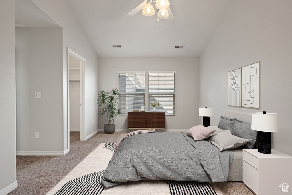 Carpeted bedroom featuring a walk in closet, lofted ceiling, a ceiling fan, baseboards, and a closet