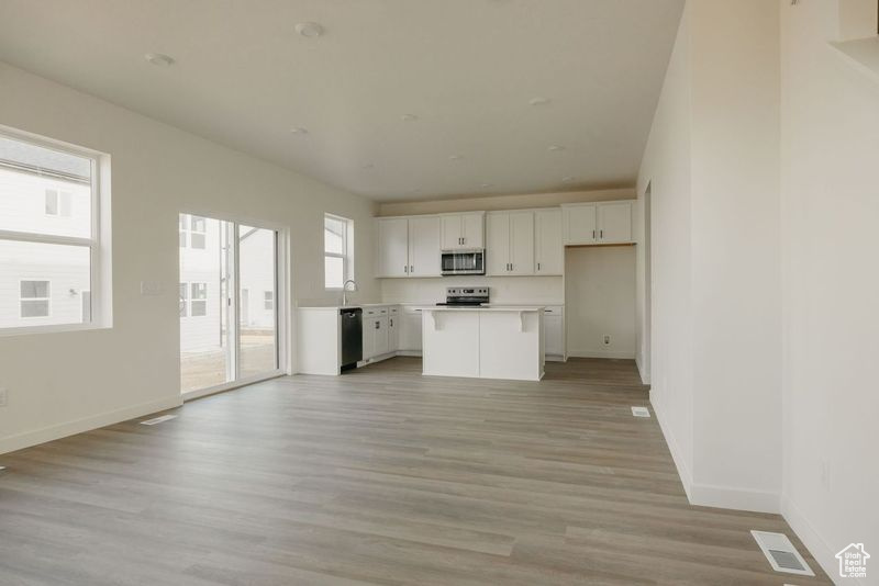 Kitchen featuring light countertops, visible vents, light wood finished floors, stainless steel appliances, and white cabinetry