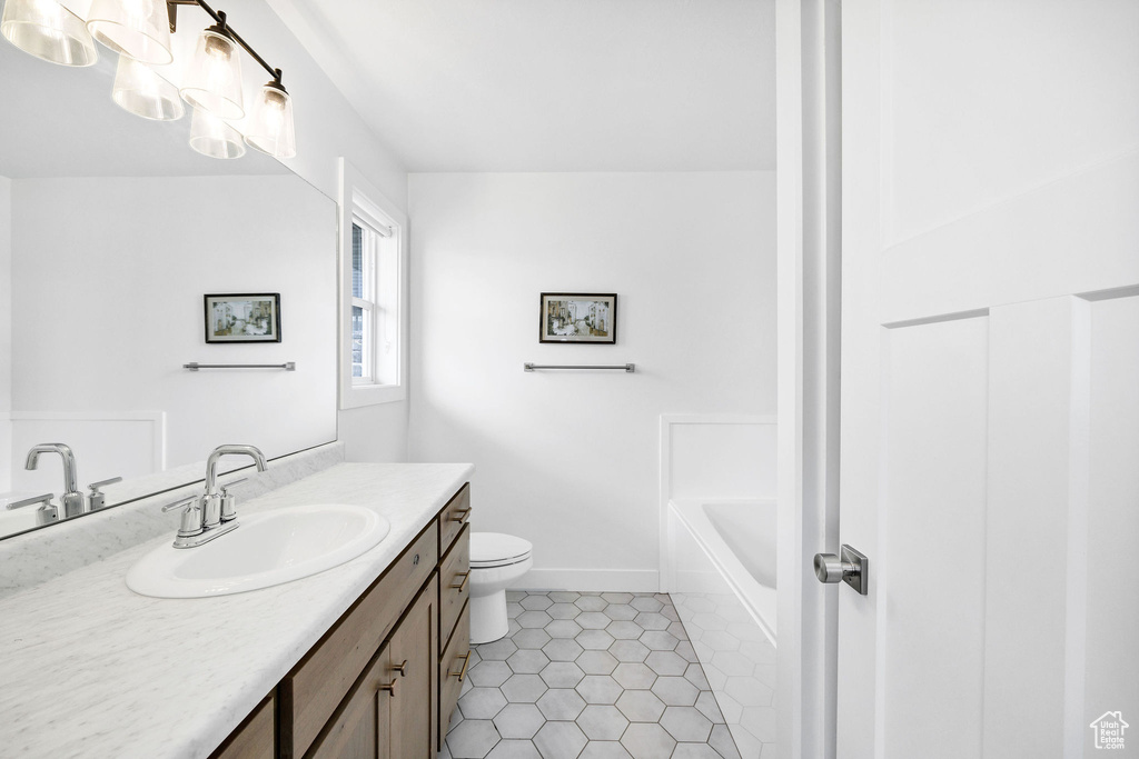 Bathroom with a bathtub, baseboards, toilet, vanity, and tile patterned flooring
