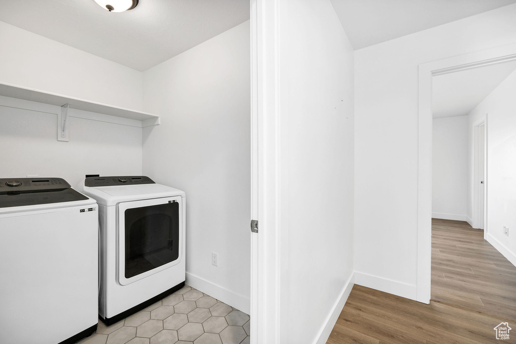 Clothes washing area featuring washer and clothes dryer, baseboards, laundry area, and light wood-type flooring