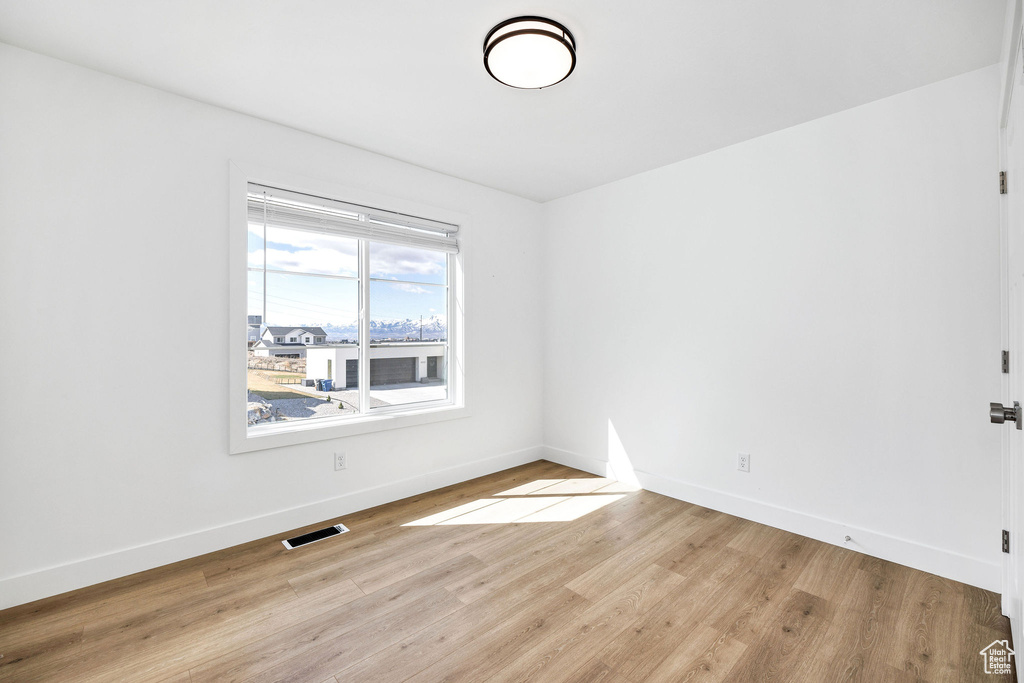 Spare room with baseboards, visible vents, and light wood-type flooring