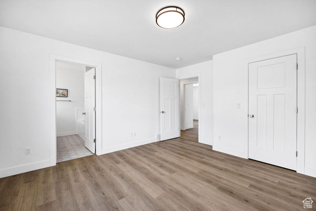 Unfurnished bedroom featuring baseboards, connected bathroom, and wood finished floors
