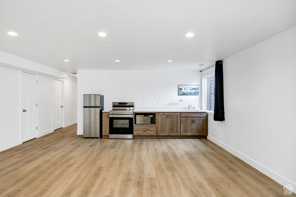 Kitchen featuring light countertops, a sink, light wood finished floors, stainless steel appliances, and recessed lighting