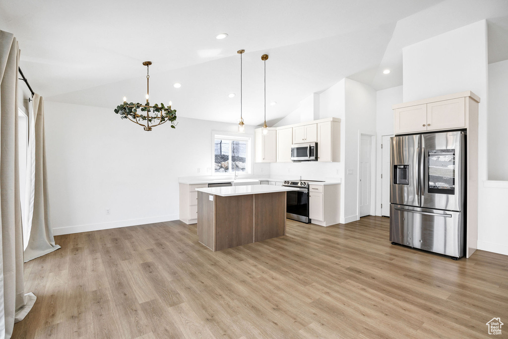 Kitchen featuring light countertops, light wood-style flooring, a chandelier, appliances with stainless steel finishes, and a center island